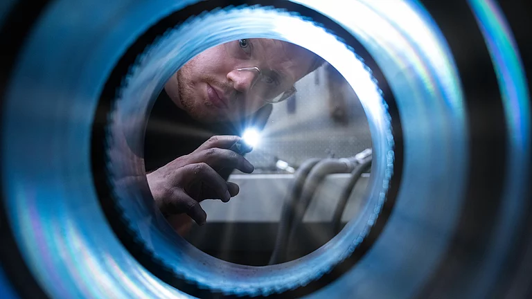 Ein Mann macht eine Sichtkontrolle der Innenverzahnung vom Zylinder