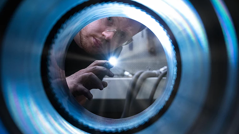 A man is carrying out a visual inspection of the internal threads of the cylinder