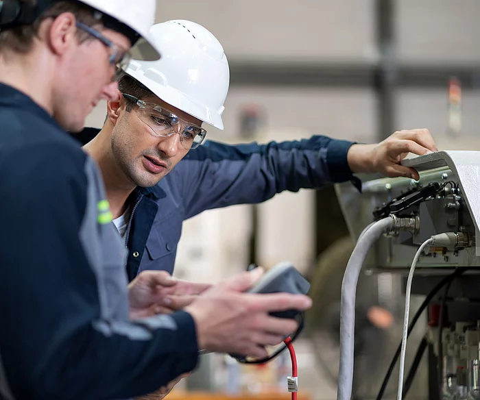 Zwei Gesco Mitarbeiter stellen eine Maschine ein
